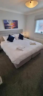 a bedroom with a large white bed with blue pillows at Riverside Apartment in Ayr