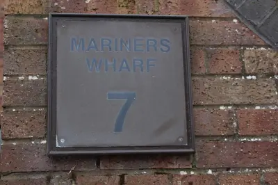 a sign on a brick wall with the number at Riverside Apartment in Ayr