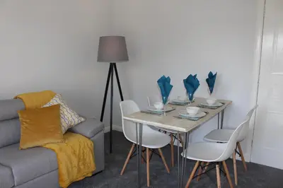 a dining room with a table with chairs and a couch at Riverside Apartment in Ayr