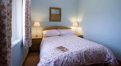 a bedroom with a bed with a book on it at Caberfeidh Cottage in Bruichladdich