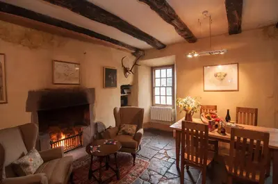 a living room with a fireplace and a table and chairs at Barns Tower in Peebles