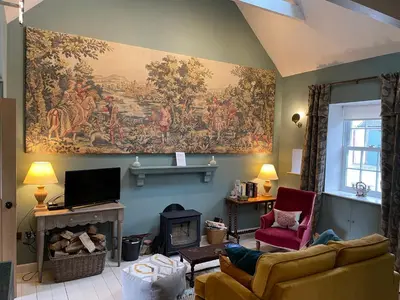 a living room with a large tapestry on the wall at Barns Bothy in Peebles