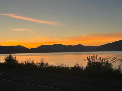 a sunset over a lake with mountains in the background at The Wee Cottage by the Ferry in Gourock