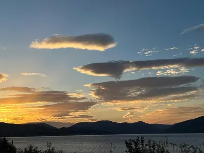a sunset over a body of water with mountains at The Wee Cottage by the Ferry in Gourock