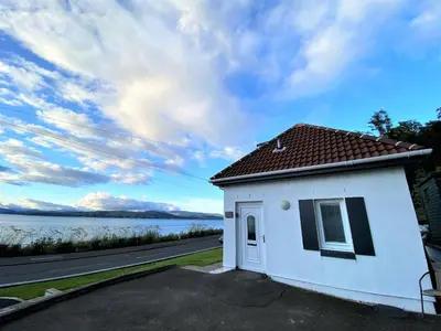 a white house with a view of the water at The Wee Cottage by the Ferry in Gourock