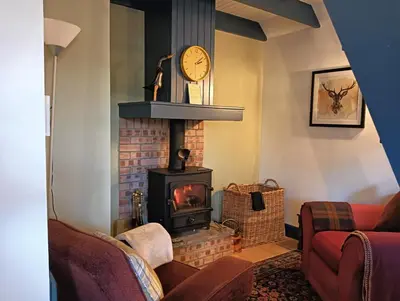 a living room with a fireplace and a clock at The Bothy Claymires Loch Lomond & Stirling in Buchlyvie