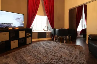 a living room with a flat screen tv and red curtains at Ayr Apartment with Sea and Countryside views in Ayr