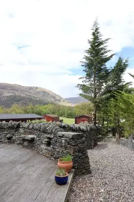 a stone wall and two potted plants on a wooden deck at Lodge 38 Rowardennan , Loch Lomond in Glasgow