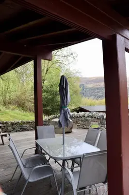 a glass table and chairs on a porch with a view at Lodge 38 Rowardennan , Loch Lomond in Glasgow