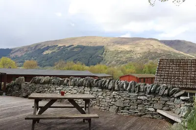 a picnic table on a deck with a stone wall at Lodge 37 Rowardennan, Loch Lomond in Glasgow