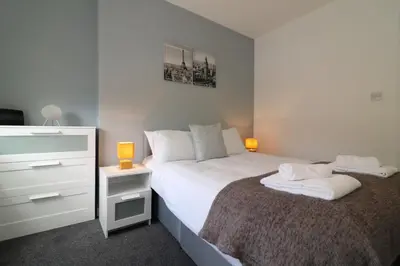 a bedroom with a bed and a dresser with two lamps at Signature - Newbattle House in Chapelhall