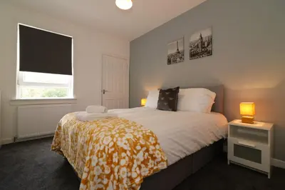 a bedroom with a bed and a window and two lamps at Signature - Newbattle House in Chapelhall