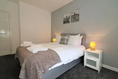 a bedroom with a large bed with two lamps on it at Signature - Newbattle House in Chapelhall