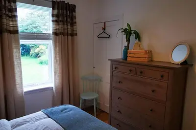 a bedroom with a dresser and a mirror next to a window at 2 Calgow Cottages in Newton Stewart