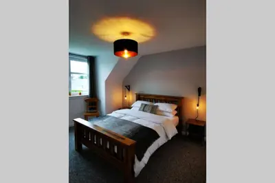 a bedroom with a large bed and a light at 2 Calgow Cottages in Newton Stewart