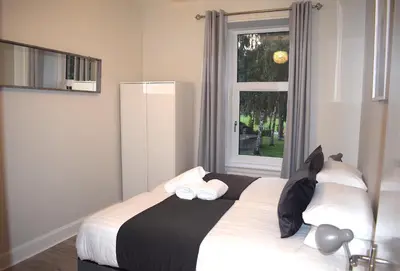 a bedroom with a bed with two pillows and a window at Kelpies Serviced Apartments- Victoria in Falkirk