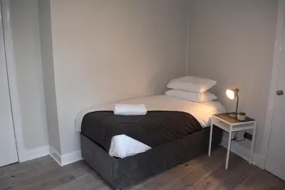 a small bed with two pillows and a table with a lamp at Kelpies Serviced Apartments- Victoria in Falkirk