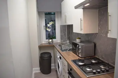 a kitchen with a sink and a stove top oven at Kelpies Serviced Apartments- Victoria in Falkirk