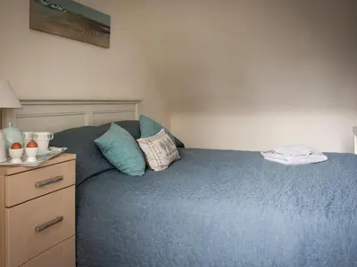 a bedroom with a blue bed and a dresser at The Grooms Cottage in Mauchline