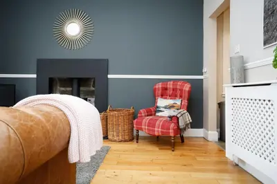 a living room with a red chair and a fireplace at Walkable 1BR Near Castle, Grassmarket, Food in Edinburgh