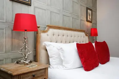a bed with red pillows and a red lamp on a table at Walkable 1BR Near Castle, Grassmarket, Food in Edinburgh