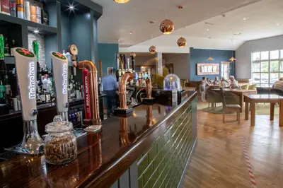 a bar in a pub with people sitting in the background at The Boat House in Kilsyth