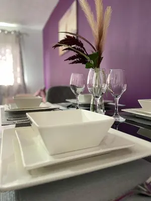 a table with a white plate and wine glasses at Chic 2 Bed Apartment with Free Parking- Recently Redecorated, 10 Minutes to City Centre in Edinburgh