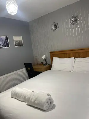 a white towel laying on a bed in a bedroom at Chic 2 Bed Apartment with Free Parking- Recently Redecorated, 10 Minutes to City Centre in Edinburgh