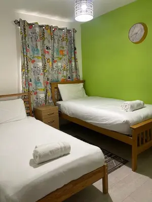 a room with two beds and a clock on the wall at Chic 2 Bed Apartment with Free Parking- Recently Redecorated, 10 Minutes to City Centre in Edinburgh