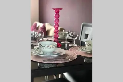 a table with a pink candlesticks and plates and glasses at Chic 2 Bed Apartment with Free Parking- Recently Redecorated, 10 Minutes to City Centre in Edinburgh