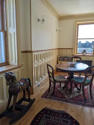a room with a wooden table and chairs and a table and a table at Kirkview House in Moffat