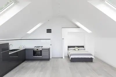 a white room with a bed and a kitchen at 1 Bed Studio - Sleeps 4 - Parking - Wifi in Saint Davids