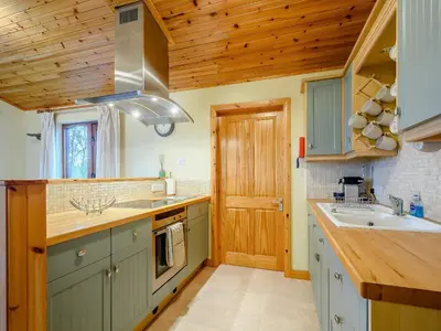 a kitchen with green cabinets and a wooden ceiling at Ard Cuan in Torbeg