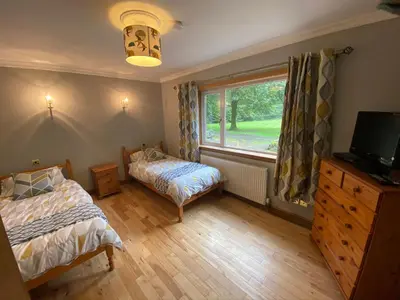 a bedroom with two beds and a window at Country Cottage Sleeps 6 w Hot Tub & Dog-Friendly in Moniaive