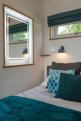a bedroom with a bed with a mirror and a window at Bonnie Barns - Adults Only Luxury Lodges with hot tubs in Luss