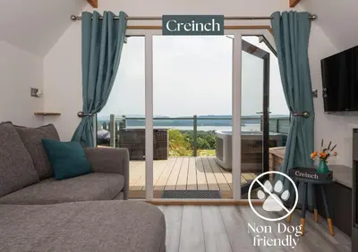 a living room with a sliding glass door to a deck at Bonnie Barns - Adults Only Luxury Lodges with hot tubs in Luss