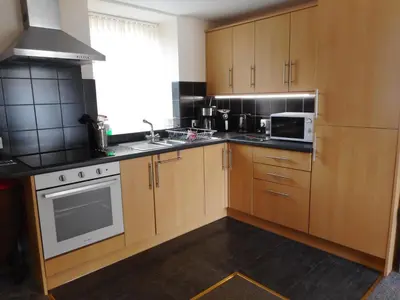 a kitchen with wooden cabinets and a microwave at DairyCottage, 5, TELFORD MEWS BEATTOCK in Moffat