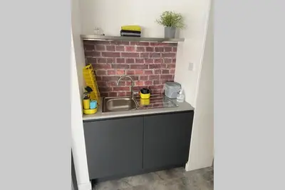 a kitchen with a sink and a brick wall at Dalgety Bay Luxury Studio Apartment in Saint Davids