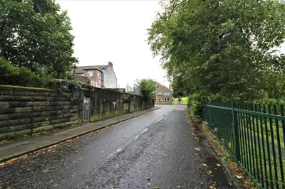 an empty street with a fence and a house at Signature - Linden Cottage Room 1 in Airdrie