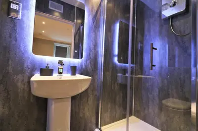 a bathroom with a sink and a shower with a mirror at Signature - Linden Cottage Room 2 in Airdrie