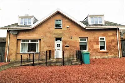 a brick house with a white door and a fence at Signature - Linden Cottage Room 3 in Airdrie