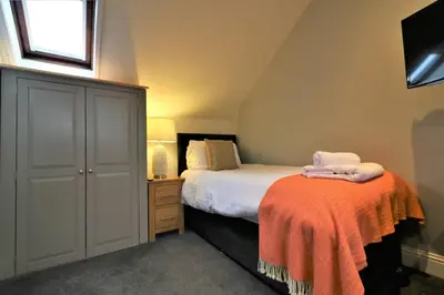 a bedroom with a bed and a dresser with towels on it at Signature - Linden Cottage Room 4 in Airdrie