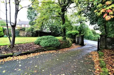 a brick path in a park with trees and leaves at Signature - Linden Cottage Room 4 in Airdrie