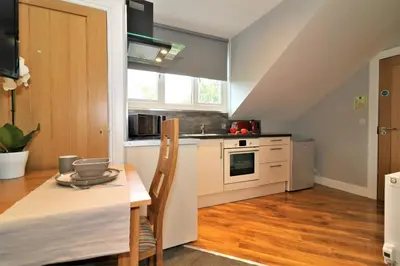 a kitchen with a dining table and a kitchen with white cabinets at Signature - Linden Cottage Room 4 in Airdrie