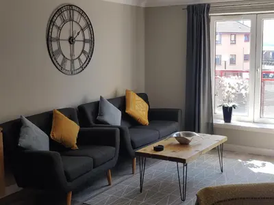 a living room with two couches and a clock on the wall at Anchors Away in Ayr