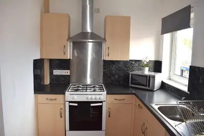 a kitchen with a stove and a microwave at Kelpies Serviced Apartments- Campbell in Pumpherston