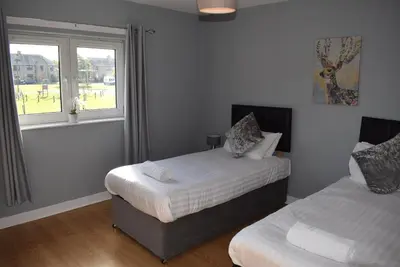 a bedroom with two beds and a window at Kelpies Serviced Apartments- Campbell in Pumpherston