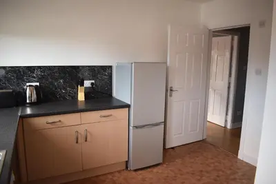 a kitchen with a white refrigerator in a room at Kelpies Serviced Apartments- Campbell in Pumpherston