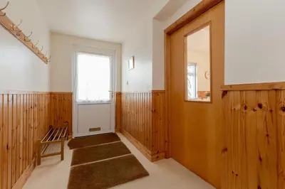 a hallway with wooden paneling and a door and a window at Doonans Cottage in Maybole