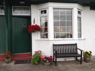 a bench sitting outside of a house with flowers at Eilean View in Lamlash